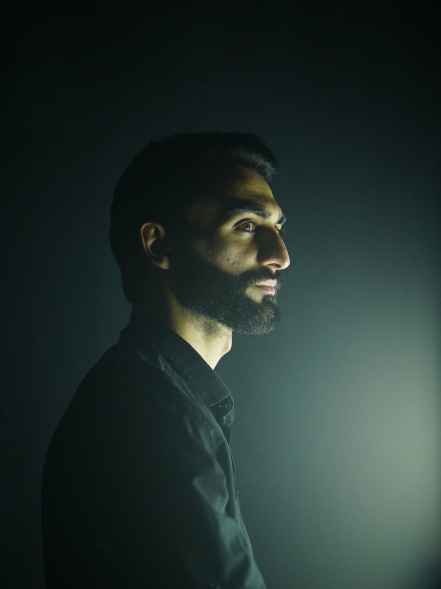 Dramatic headshot with side lighting against a dark background